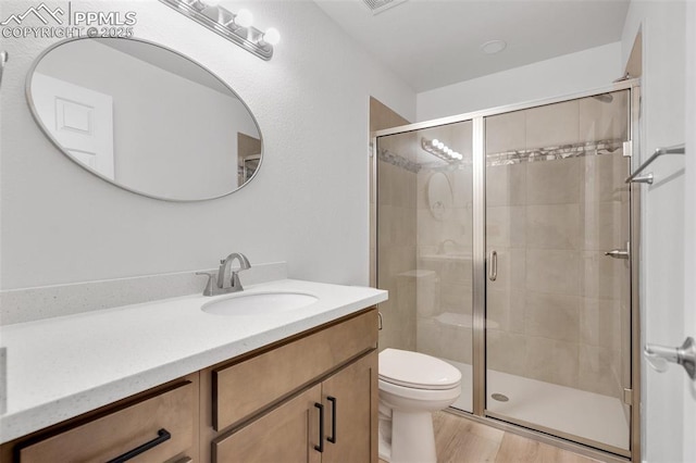 bathroom featuring vanity, hardwood / wood-style flooring, toilet, and walk in shower