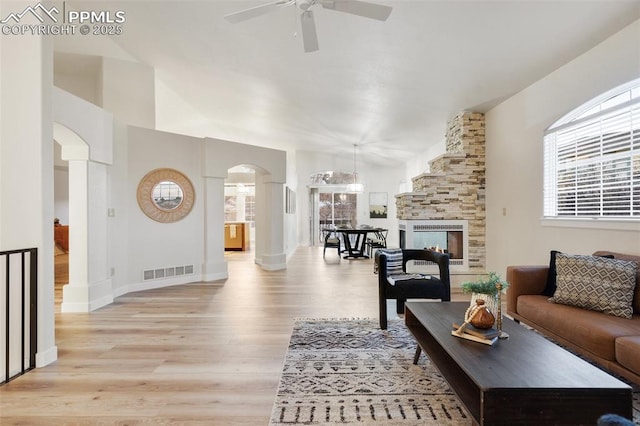 living room featuring ceiling fan, a fireplace, and light wood-type flooring