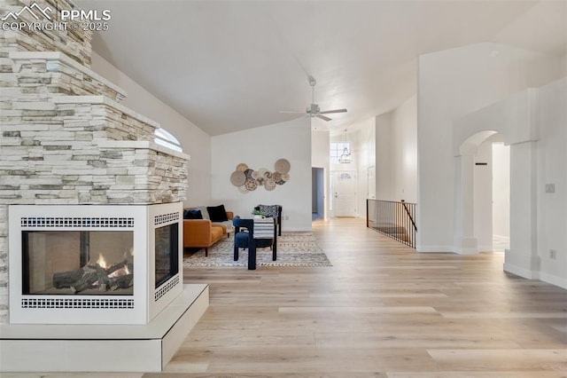 unfurnished living room with ceiling fan, light wood-type flooring, a fireplace, and lofted ceiling