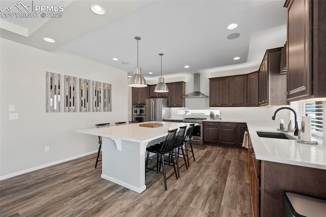 kitchen featuring pendant lighting, a kitchen island, wall chimney exhaust hood, high quality appliances, and sink