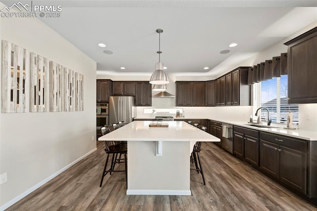 kitchen with pendant lighting, a kitchen island, sink, appliances with stainless steel finishes, and a breakfast bar area