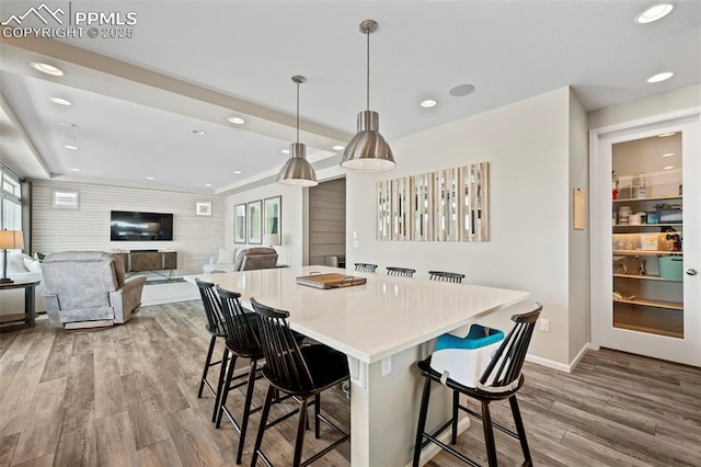 kitchen with a breakfast bar, hanging light fixtures, light hardwood / wood-style flooring, and a center island