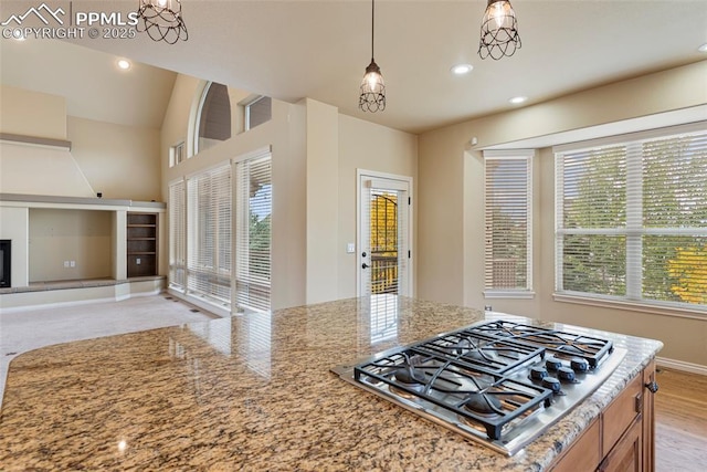 kitchen featuring hanging light fixtures, light stone counters, stainless steel gas stovetop, and a notable chandelier