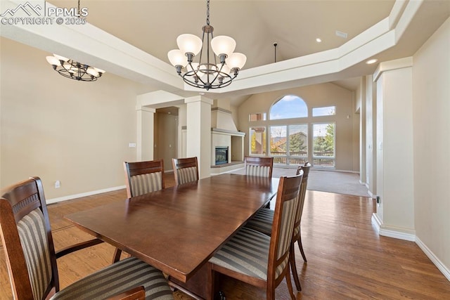 dining area with a chandelier, a towering ceiling, and hardwood / wood-style flooring