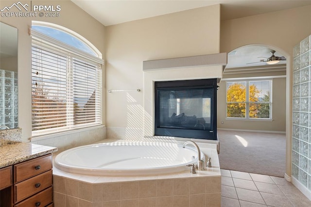 bathroom featuring vanity, a relaxing tiled tub, tile patterned floors, and ceiling fan