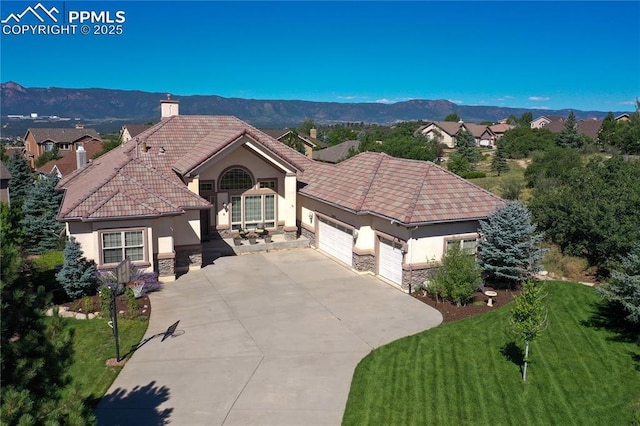 mediterranean / spanish-style house with a mountain view, a front lawn, and a garage