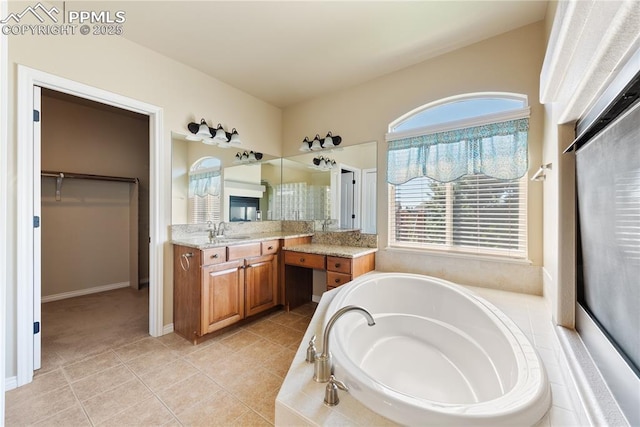 bathroom featuring tile patterned flooring, vanity, and a relaxing tiled tub