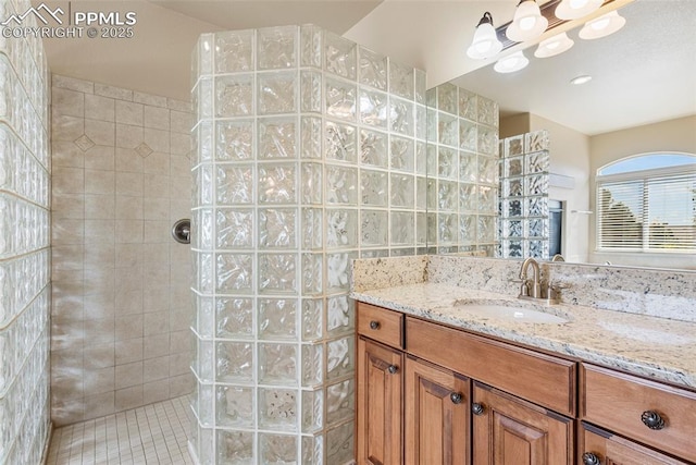 bathroom with a tile shower, vanity, and tile patterned floors