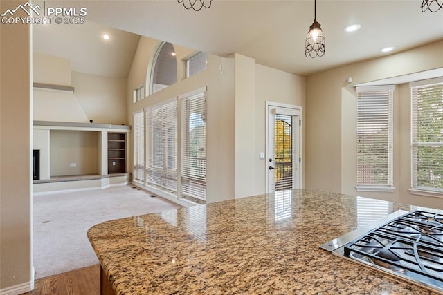 kitchen with stainless steel gas stovetop, light stone countertops, decorative light fixtures, and a chandelier