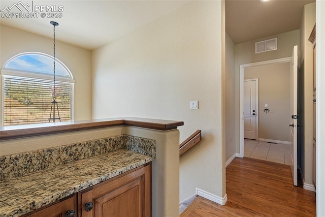 interior space featuring decorative light fixtures, light hardwood / wood-style floors, and stone countertops