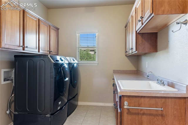 laundry room featuring separate washer and dryer, sink, light tile patterned floors, and cabinets