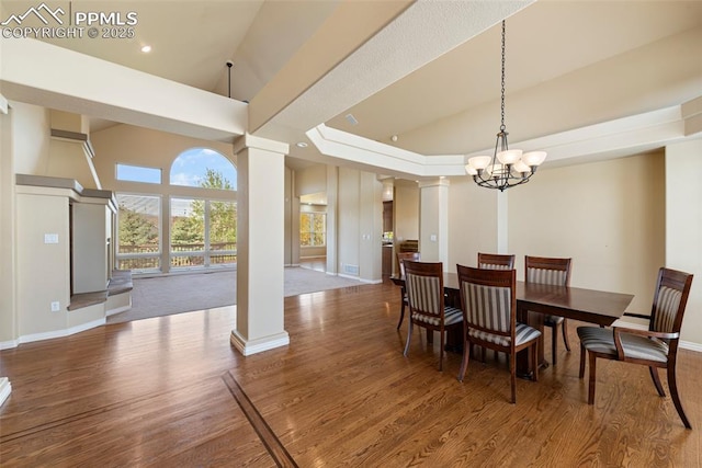 dining area featuring ornate columns, wood-type flooring, and a notable chandelier