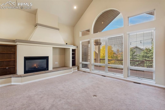 unfurnished living room featuring carpet flooring and high vaulted ceiling