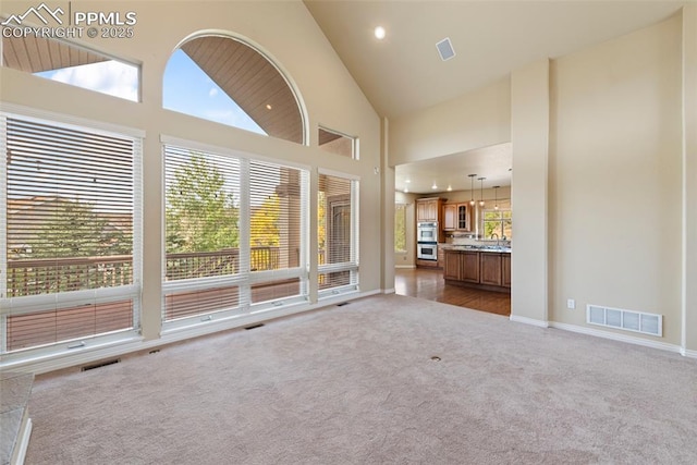 unfurnished living room with carpet and high vaulted ceiling