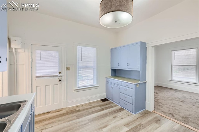 kitchen with sink, light hardwood / wood-style flooring, and blue cabinets