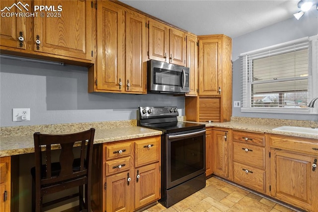 kitchen featuring light stone counters, black range with electric stovetop, and sink