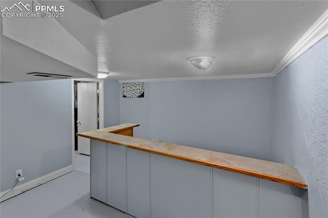 bar featuring white cabinets, ornamental molding, and a textured ceiling