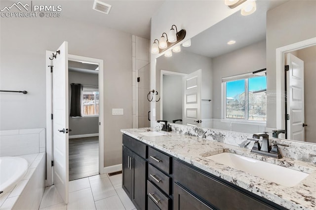 bathroom featuring vanity, tiled bath, tile patterned floors, and a healthy amount of sunlight