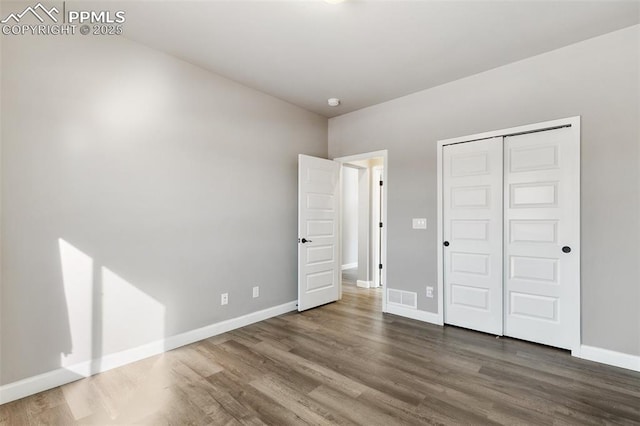 unfurnished bedroom with a closet and dark wood-type flooring