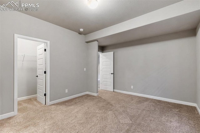 unfurnished bedroom with a spacious closet, a closet, and light carpet