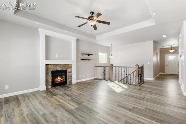 unfurnished living room with hardwood / wood-style floors, ceiling fan, and a tray ceiling