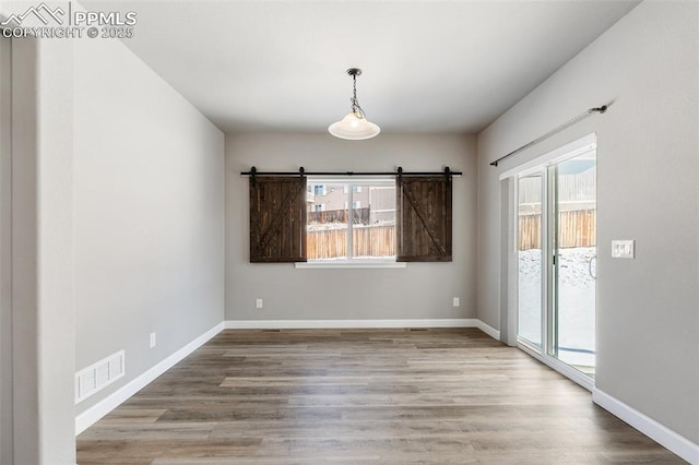 unfurnished room featuring hardwood / wood-style floors and a barn door