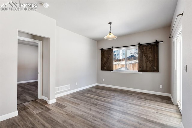 unfurnished dining area featuring hardwood / wood-style floors and a barn door