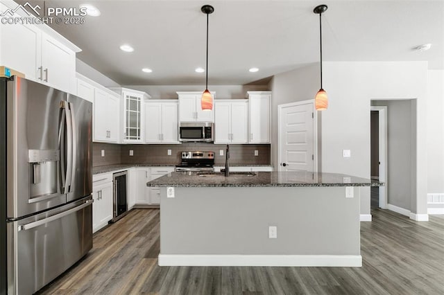 kitchen featuring pendant lighting, stainless steel appliances, a kitchen island with sink, and sink