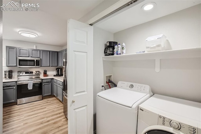 laundry room with light hardwood / wood-style floors and washer and clothes dryer