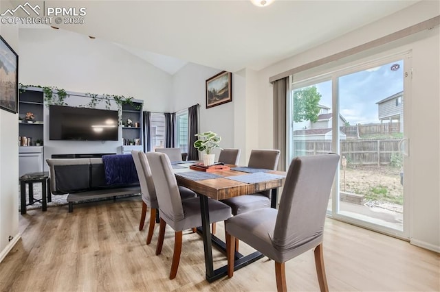 dining area with light wood-type flooring and vaulted ceiling