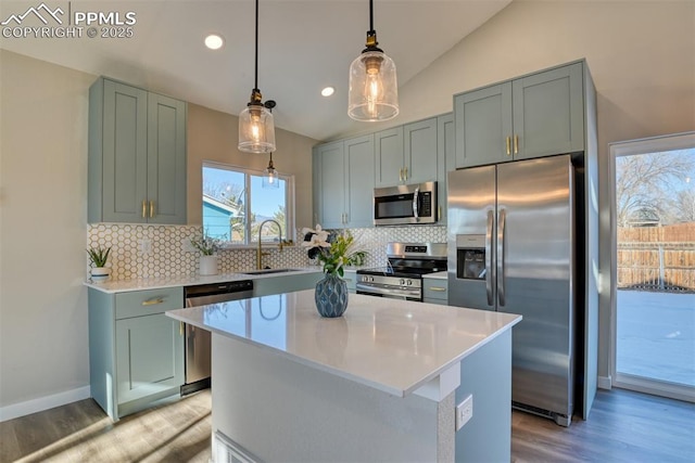 kitchen featuring stainless steel appliances, a center island, sink, decorative light fixtures, and lofted ceiling