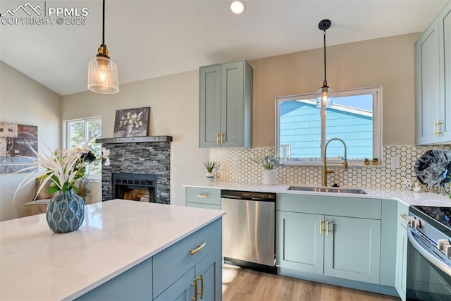 kitchen with stainless steel appliances, sink, a fireplace, tasteful backsplash, and hanging light fixtures