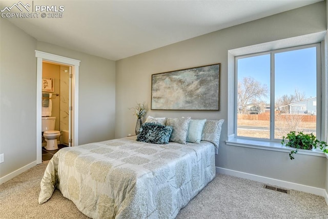 carpeted bedroom featuring ensuite bath and multiple windows