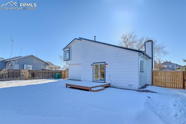 snow covered rear of property with a deck