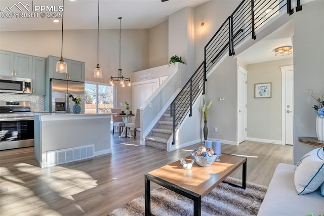 living room featuring high vaulted ceiling, a chandelier, and wood-type flooring