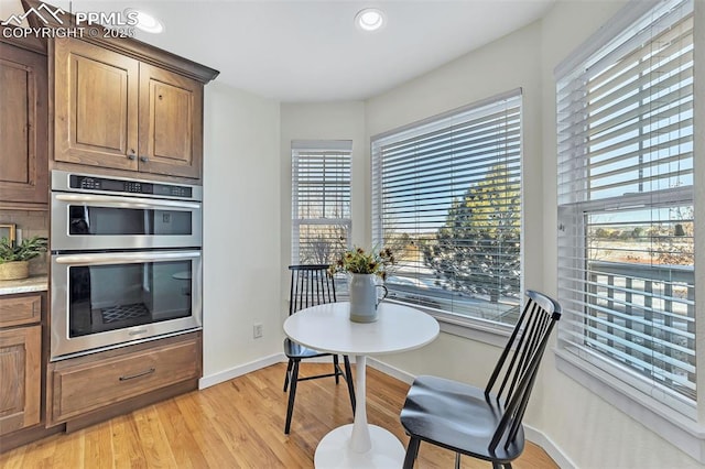 kitchen with light hardwood / wood-style floors, double oven, and a healthy amount of sunlight