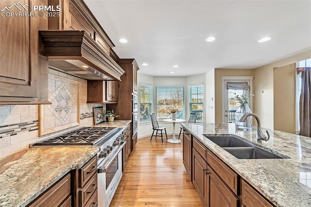 kitchen with light stone countertops, decorative backsplash, sink, and stainless steel appliances