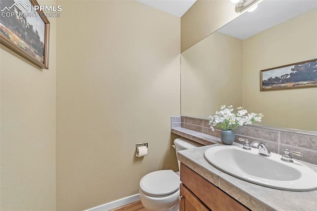 bathroom with vanity, hardwood / wood-style flooring, toilet, and backsplash