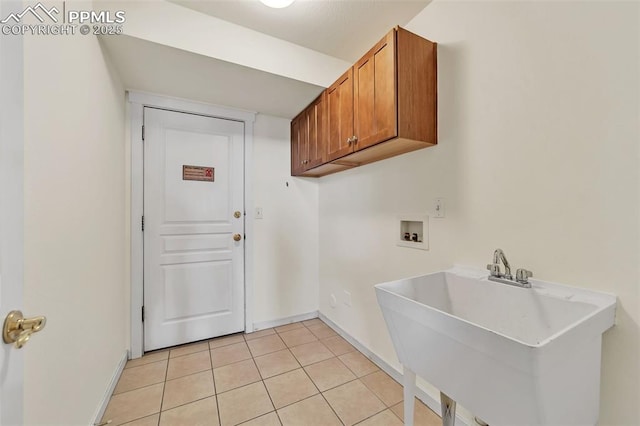 washroom featuring hookup for a washing machine, light tile patterned floors, cabinets, and sink