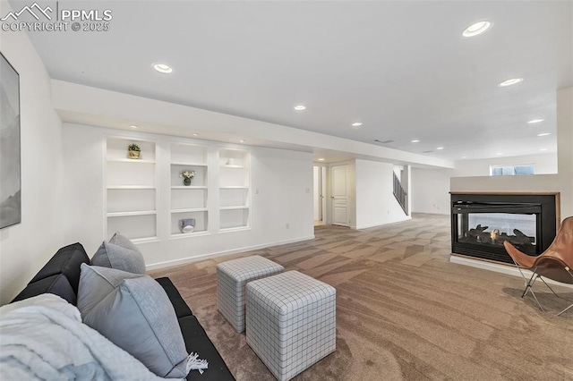 living room featuring carpet, a multi sided fireplace, and built in features