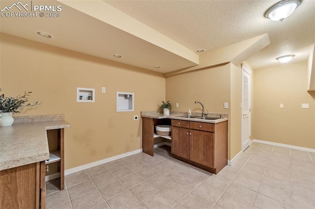 kitchen with light tile patterned floors, a textured ceiling, and sink