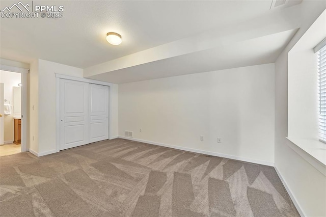 unfurnished bedroom featuring carpet flooring, ensuite bath, and a closet