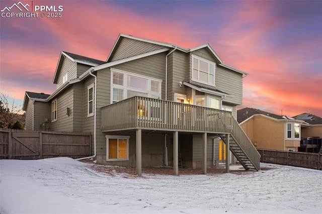 snow covered rear of property with a deck