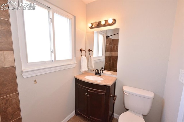 bathroom featuring tiled shower, plenty of natural light, vanity, and toilet