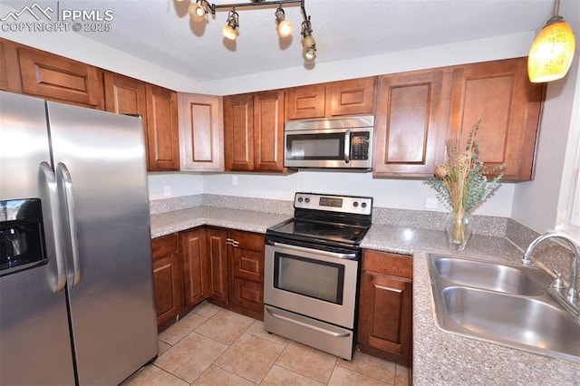 kitchen with appliances with stainless steel finishes, pendant lighting, sink, and light tile patterned floors