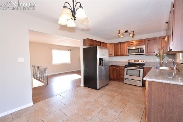 kitchen featuring stainless steel appliances, sink, light stone counters, hanging light fixtures, and a chandelier