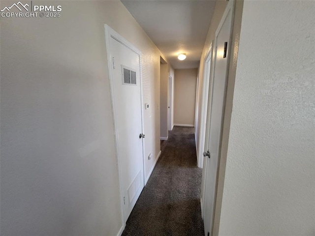 hallway featuring carpet, visible vents, and baseboards