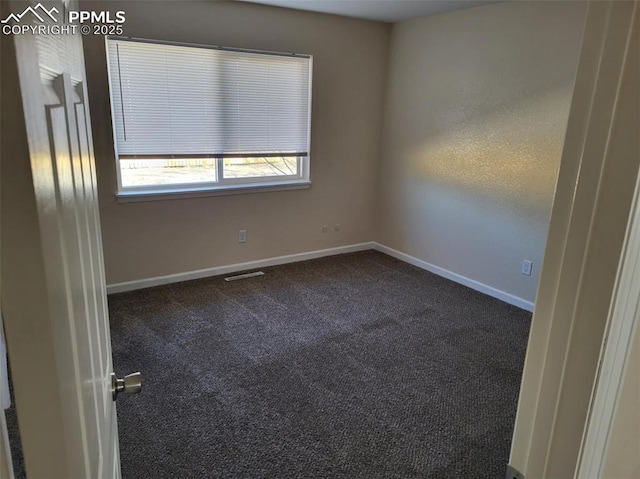 unfurnished room featuring dark colored carpet, visible vents, and baseboards