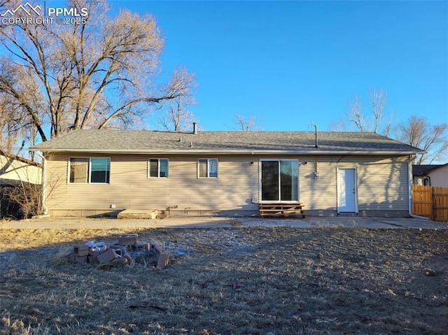 rear view of house featuring entry steps, fence, and a patio