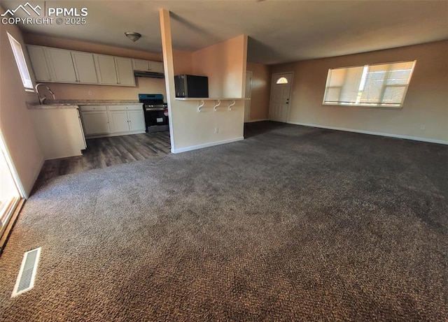 kitchen with visible vents, electric stove, open floor plan, dark colored carpet, and white cabinetry